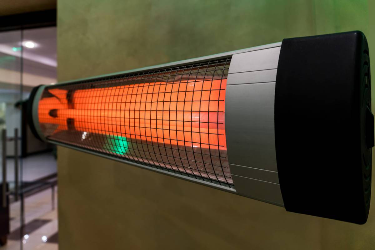 Infrared patio heater mounted on a wall, glowing orange.