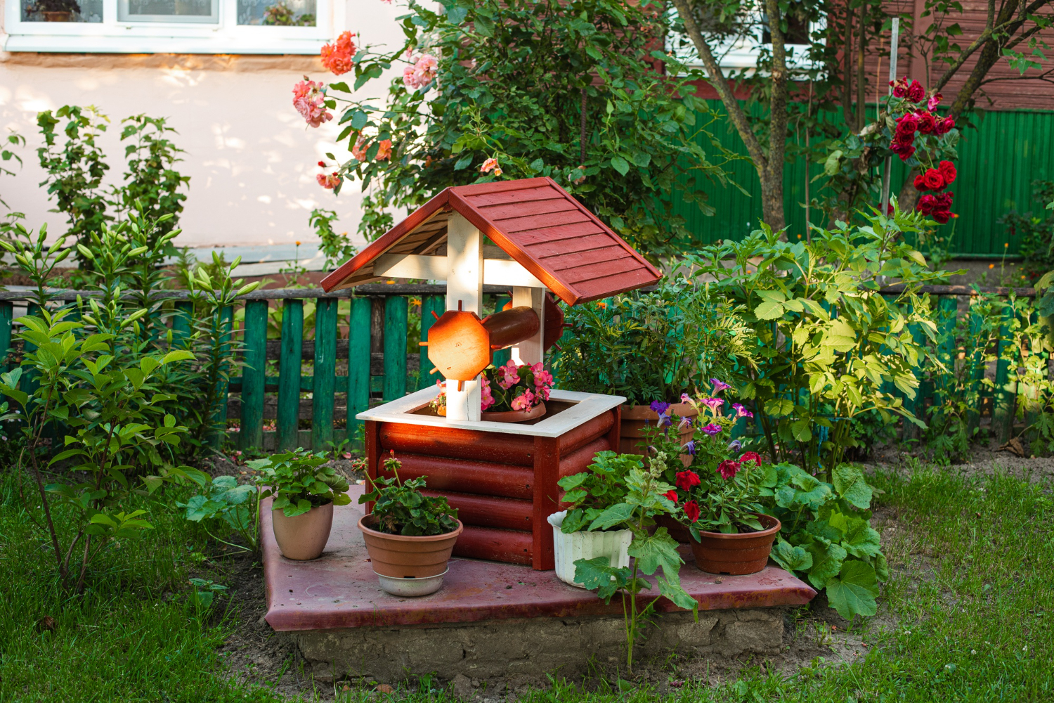 Decorative garden wishing well surrounded by flowers and greenery, part of small garden design.