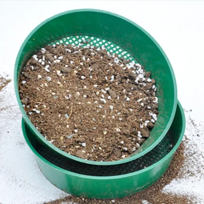 Green plastic garden sieve with soil and perlite, 3mm mesh.