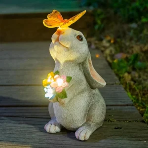 Solar bunny garden statue with butterfly and flowers, glowing at night.