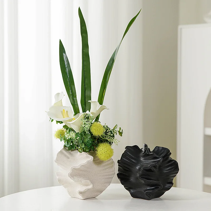 Modern vases: White ceramic vase with floral arrangement, black sculptural vase.