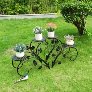 Black metal plant stand with flowers on a green lawn, garden decor.