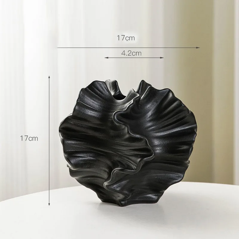 Black ceramic vase with a ruffled, organic design. 17cm tall, 17cm wide, and 4.2cm at the opening.